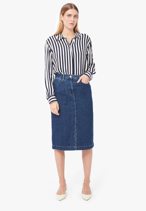 Chemise à rayures à manches longues, associée à une jupe en jean longueur genou dans un délavé moyen et des talons beige pointus.
