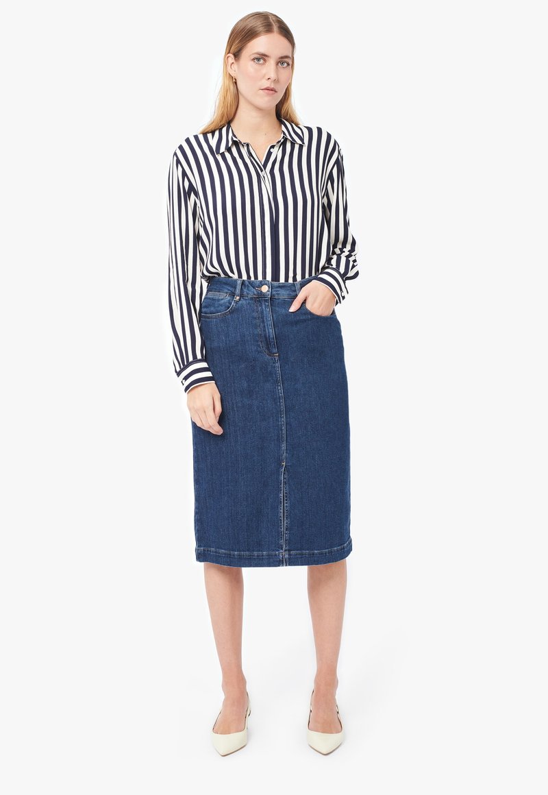 Camicia a righe con maniche lunghe, abbinata a una gonna di jeans lunga fino al ginocchio in un lavaggio medio e décolleté beige a punta.