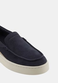Scarpa slip-on in suede blu navy con punta arrotondata, suola beige a contrasto e dettagli di cucitura sottili lungo il vamp e il lato.
