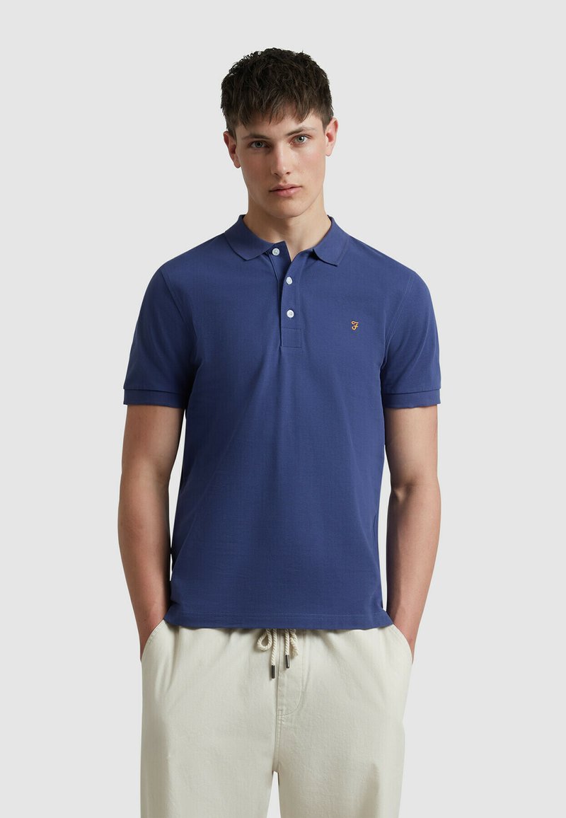 Polo marine en coton, avec un col, des manches courtes et un petit logo brodé jaune sur la poitrine.