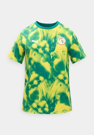 Zelena in rumena kravata-dye majica s okrolim izrezom, logotipom Pume na desni strani prsnega koša in emblemom nogometne zveze Senegala na levi strani prsnega koša.