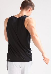 Black sleeveless tank top featuring a smooth, lightweight fabric, with a relaxed fit and curved hem at the bottom, shown from the back.