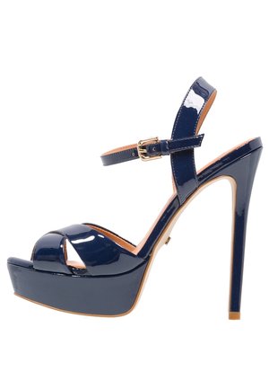 Navy patent leather platform heels with a peep-toe design, thin ankle strap with gold buckle, and a high stiletto heel.