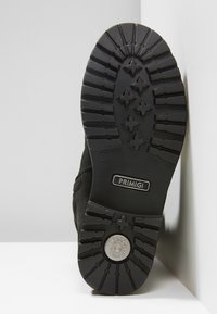 Semelle de botte noire avec des profondes rainures, insert en métal pour absorber les chocs, taille 31, et logo "PRIMIGI" au centre.