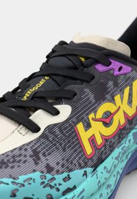 HOKA Speedgoat 6 sneaker features a black textured upper, multicolored accents, and a chunky turquoise sole with a rugged pattern.