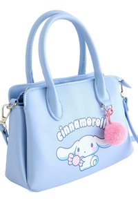 Lyseblå syntetisk håndtaske med korte håndtag, med en "Cinnamoroll"-grafik og en lyserød pompom-charme fastgjort.