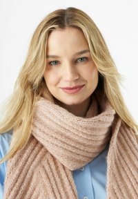 Hellrosa, gestrickter Schal mit einer gerippten Textur, um den Hals drapiert. Weiches Wollmaterial sorgt für Wärme, kombiniert mit einem blauen Hemd mit Knöpfen.