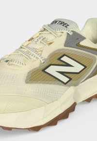 Μπεζ και εκρού αθλητικό παπούτσι New Balance με κορδόνια με σχέδιο, υφασμένη πλαϊνή επιφάνεια και καφέ σόλα με λαβή.
