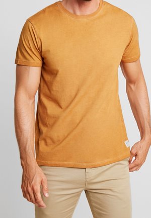 Kortærmet, rundhalset t-shirt i en ensfarvet sennepsgul farve, lavet af blød bomuld med en subtil tekstur og et lille mærke på sømmen.