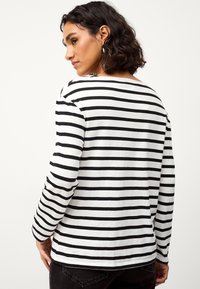 Zwart-witte gestreepte longsleeve shirt met een bootnek, zachte katoenmaterialen en een afgeronde zoom aan de achterkant.