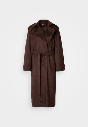 Trench coat marrón de ante con un frente de doble botonadura, gran cuello, cintura ceñida con cinturón y bolsillos laterales. Presenta puños abotonados y una textura suave.
