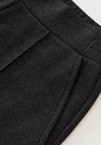 Svarta ribbade byxor med framfickor och elastisk midja, med en subtil metalltråddetalj.