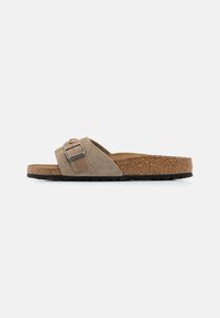 Sandalo scivoloso in suede marrone con una soletta in sughero, caratterizzato da una fibbia metallica rettangolare e una suola in gomma texturizzata.