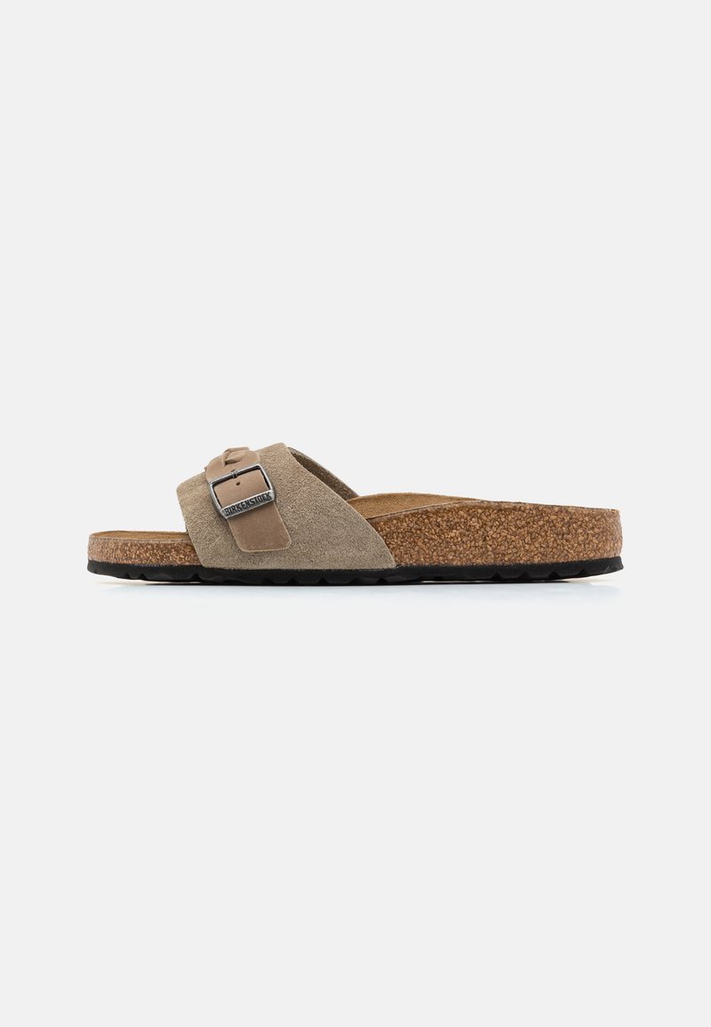 Sandalo scivoloso in suede marrone con una soletta in sughero, caratterizzato da una fibbia metallica rettangolare e una suola in gomma texturizzata.