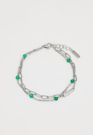 Bracelet en chaîne argentée avec des perles vertes, incluant un mélange de finitions texturées et lisses, et une fermeture à fermoir en forme de homard avec une étiquette gravée.