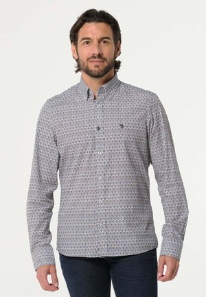 Lange mouwen shirt van lichtgrijze stof met een geometrisch patroon in blauw en bruin. Voorzien van een button-down kraag en knopen aan de voorkant.