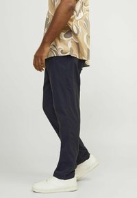 Pantalones navy de tejido ligero, con un corte recto. Combinados con una camisa de manga corta con estampado y zapatillas blancas.