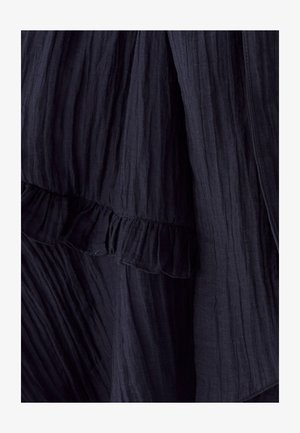 Mekko, jossa on laivastonsininen, ryppyinen kangas ja röyhelöhelma. Ominaisuudet pehmeä tekstuuri ja virtaava muotoilu. Lähikuva tuo esiin monimutkaisia yksityiskohtia.