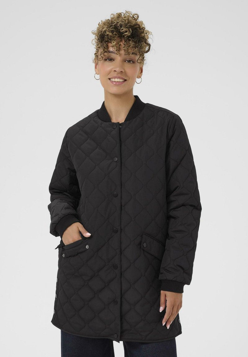 Giacca nera trapuntata con chiusura a bottoni a pressione, polsini a coste e tasche laterali. Il design presenta una texture a motivo a rombi.