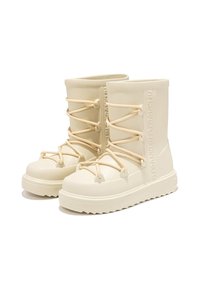 Botas de goma de color crema con un acabado texturizado, que presentan cordones en la parte frontal y un logotipo en relieve en el lateral. Suela gruesa para mayor estabilidad.