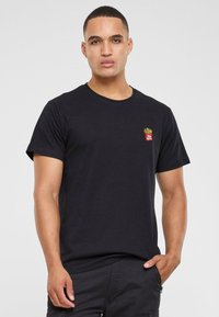 Tricou negru din bumbac, având un mic design brodat cu cartofi prăjiți pe partea stângă a pieptului. Guler clasic tip crew și mâneci scurte.