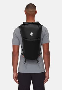 Mochila negra con un diseño aerodinámico, fabricada en un material ligero. Cuenta con un logo, correas ajustables y bolsillos con cremallera.