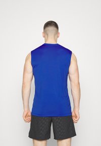 Maglietta senza maniche blu reale in tessuto morbido, dalla forma aderente, con collo rotondo. Abbinata a pantaloni corti neri con un motivo texturizzato.