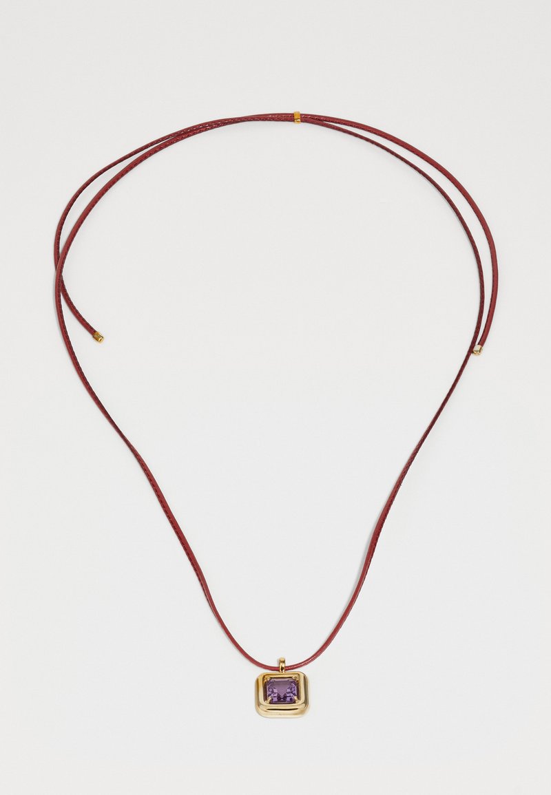 Punane nahkne kaelakee, millel on ristküliku kujuline kuldne ripats, millel on lillaka kristalli, sile tekstuur ja minimalistlik disain.