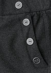 Černá denimová látka s herringbone vzorem. Obsahuje čtyři stříbrné knoflíky na légě a detail boční kapsy.