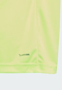Chemise verte clair à manches courtes en tissu respirant, avec le logo "CLIMACOOL" imprimé en noir près de l'ourlet, texture douce.