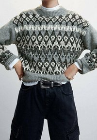 Sweter wełniany w odcieniu szarym, zdobiony wzorem w czerni i bieli. Żebrowany dekolt i mankiety. Nosi się go na białej koszuli z kołnierzykiem oraz ciemnych spodniach.