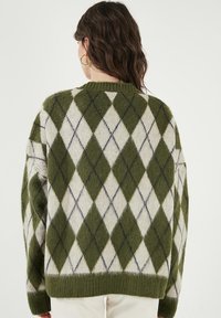 Roheline ja valge argyle-muster, pehme tekstuuriga, ülemõõdulise kujuga ning ribaga krae ja varrukateotsad. Omab diagonaalseid siniseid aktsente.