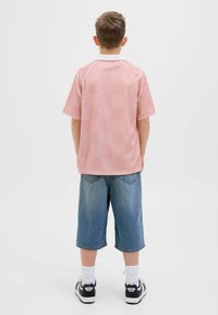 Polo de cuadros rosa de manga corta con cuello blanco, combinado con shorts de mezclilla azules claros hasta la rodilla y zapatillas negras.