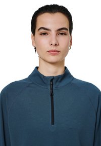 Niebieski polarowy pulower z półzipem, charakteryzujący się teksturowaną powierzchnią, czarnym zamkiem błyskawicznym oraz wysokim kołnierzem; idealny do codziennych i sportowych stylizacji.