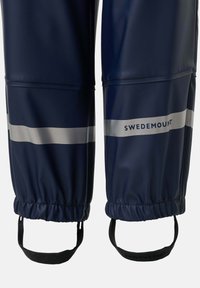 Pantalon imperméable bleu marine avec bandes argentées réfléchissantes et sangles de pied noires réglables, nom de la marque "Swedemount" sur la jambe droite.