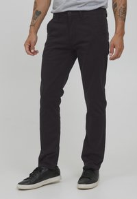 Mörklila bomullschinos med slim fit, med knäppning, sidofickor och lätt stretch för komfort. Svarta sneakers fulländar looken.