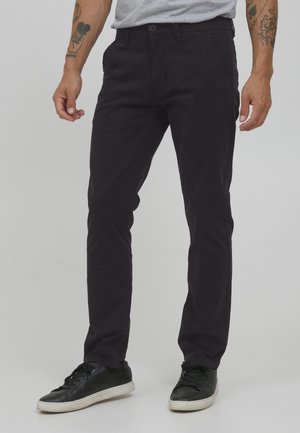 Mørk lilla bomulds chinos med slim fit, med knaplukning, sidelommer og let stræk for komfort. Sorte sneakers fuldender looket.