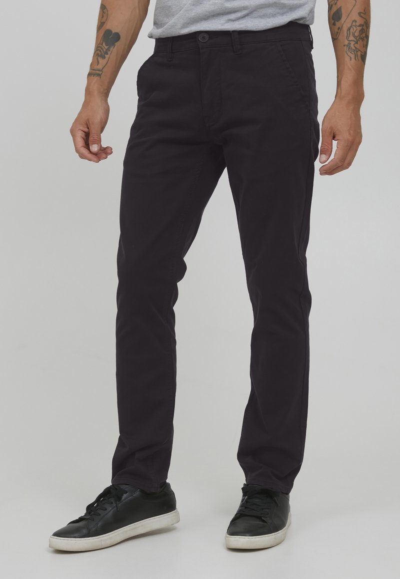 Mörklila bomullschinos med slim fit, med knäppning, sidofickor och lätt stretch för komfort. Svarta sneakers fulländar looken.