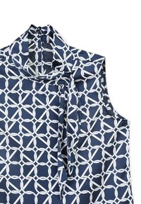 Blusa senza maniche blu navy con un motivo geometrico circolare bianco, dettaglio a cravatta al collo e una texture di tessuto liscia.