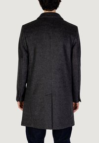 Abrigo de lana gris con cuello de solapa, corte recto y detalle de abertura trasera. Presenta puños abotonados y una tela texturizada. Vista trasera.
