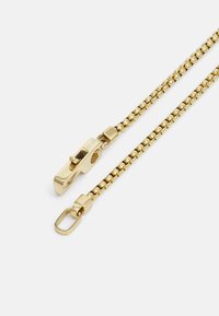Gouden metalen ketting met ronde schakels, voorzien van een sluiting en rechthoekige bevestiging. Het oppervlak is glad en glanzend, waardoor het licht reflecteert.