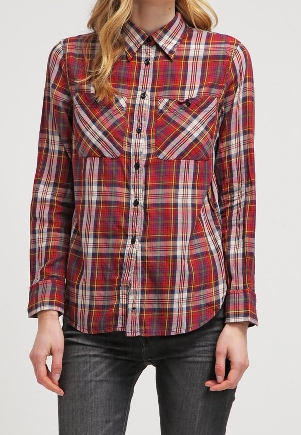 Camicia a quadri rossi e bianchi, con colletto a polo, due tasche sul petto e bottoni neri; maniche lunghe con polsini abbottonati.