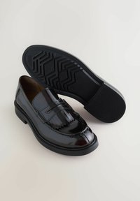 Black patent leather loafers with a fringed detail, round toe, and a textured rubber sole. Smooth finish with a contrasting matte sole.