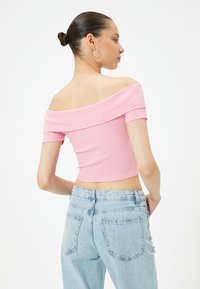 Rosa off-the-shoulder ribbad crop-top parat med ljusblå högmidjade jeans, med avslappnad passform och subtil blekning.