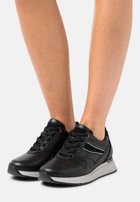 Black leather sneakers with lace-up design, feature a light grey midsole, and subtle mint green accents on the sides.