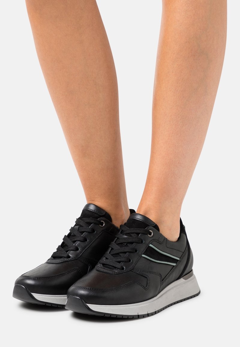 Black leather sneakers with lace-up design, feature a light grey midsole, and subtle mint green accents on the sides.
