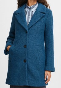 Teal wolblend jas met een geknipte kraag, drie zwarte knopen en twee zijzakken met een gestructureerde afwerking.