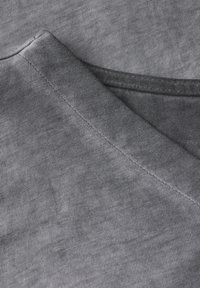 Tissu en coton gris avec une texture côtelée subtile, doté d'un décolleté en V et d'une finition propre sur les bords.