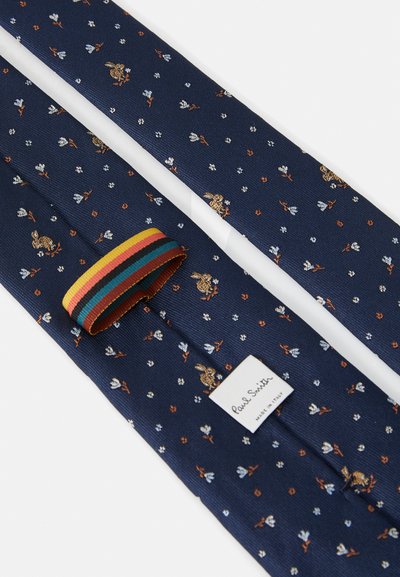 Marine slips med blomster- og kaninmotiver i gull og hvitt. Har en flerfarget stripet løkke og en hvit etikett med teksten "Paul Smith."