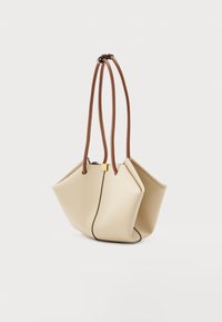 Μπεζ τσάντα από μαλακό δέρμα με δομημένο γεωμετρικό σχήμα και δύο μακριές καφέ δερμάτινες λαβές σε λευκό φόντο.
